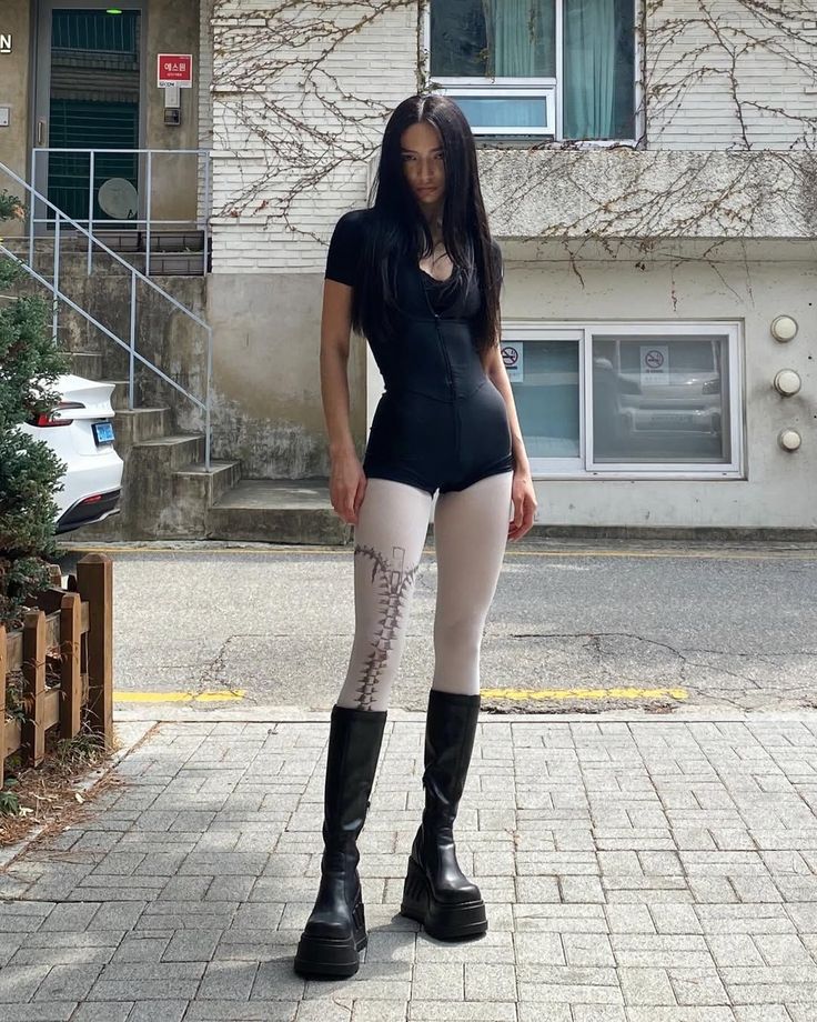 Woman with long black hair in a black bodysuit and platform boots on a street