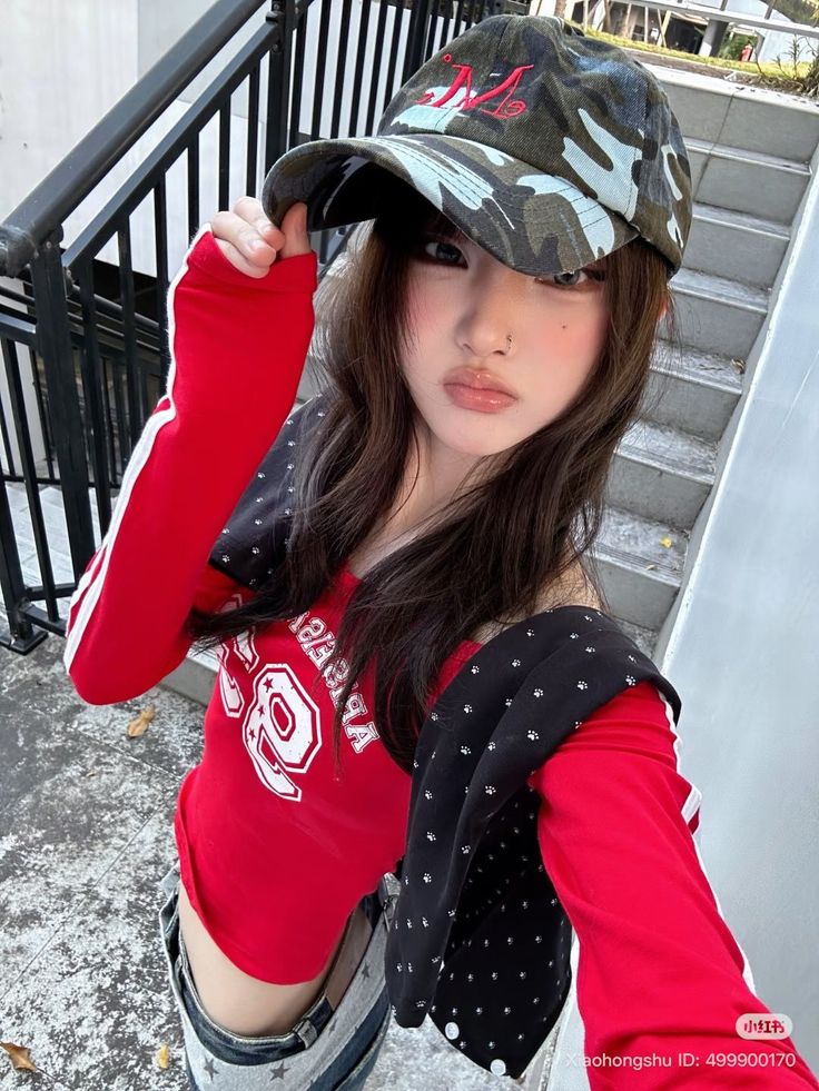 Woman in a red top and camo hat with an exposed midriff outdoors
