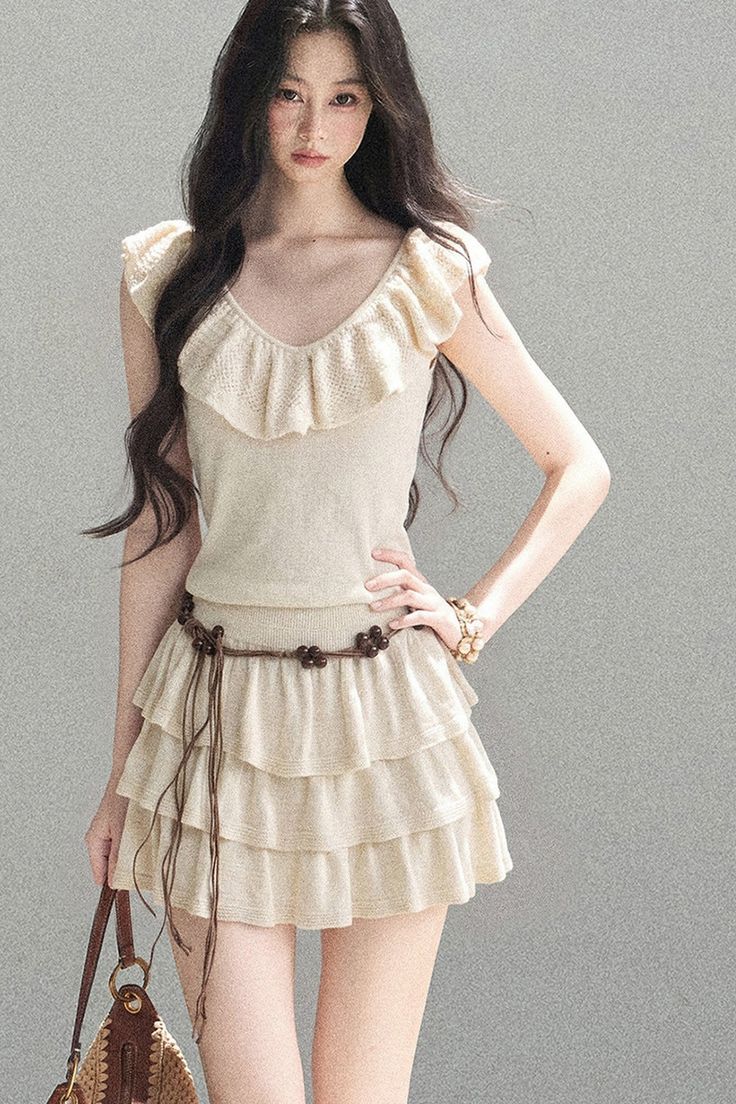 Woman with long dark hair wearing a ruffle top and tiered skirt with a beaded belt
