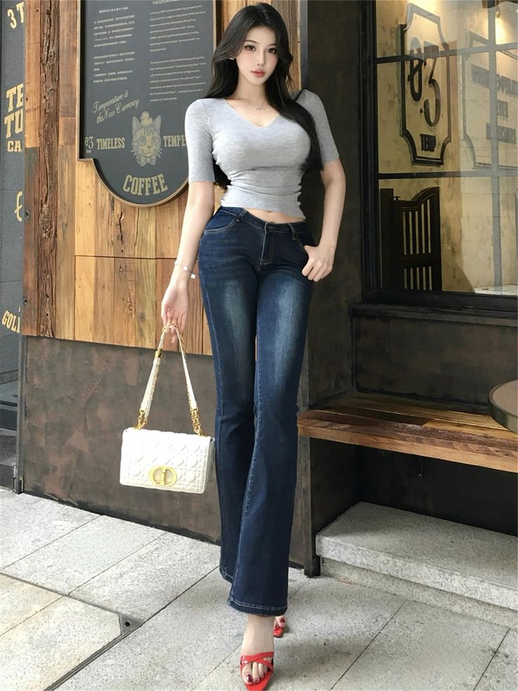 Woman with long black hair wearing a cropped top and flared jeans outdoors