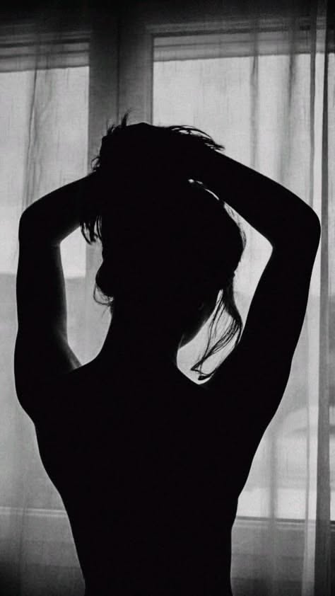 Silhouette of a person with hands behind their head, backlit by a window