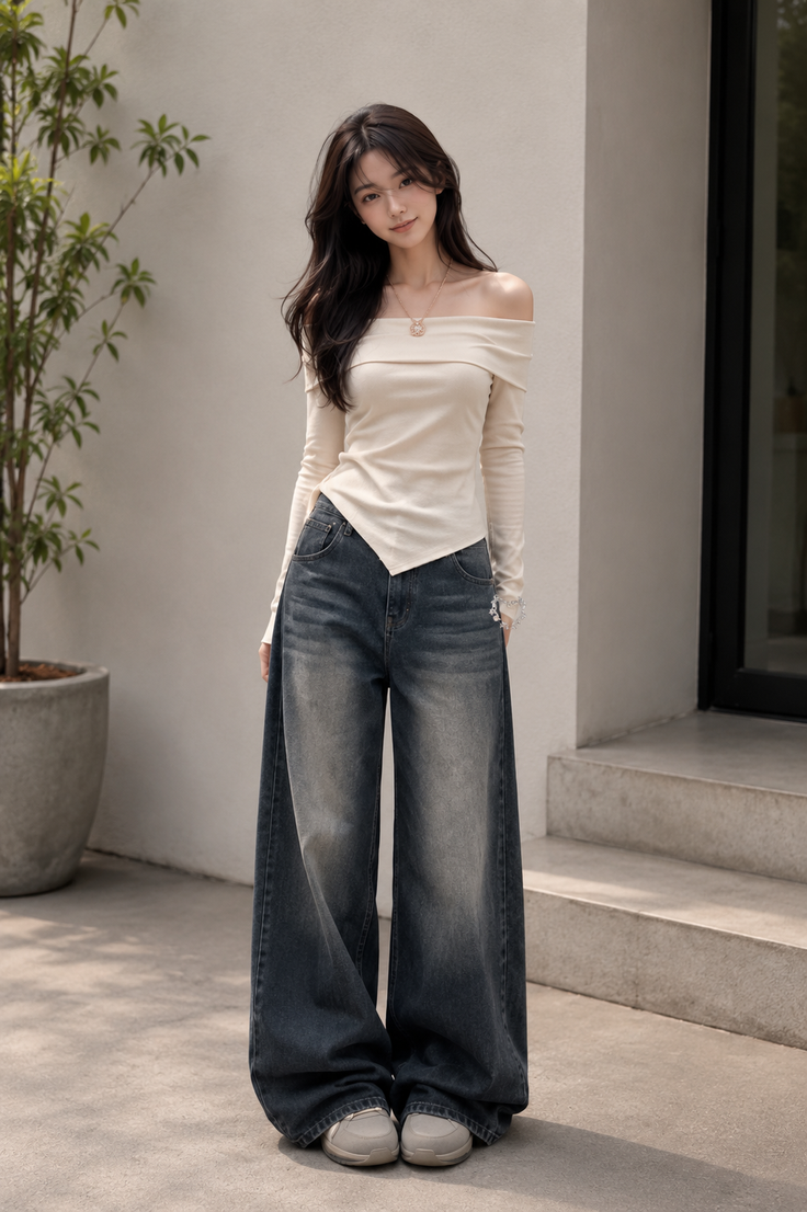 Woman with long dark hair wearing an off-shoulder top and wide-leg jeans outdoors