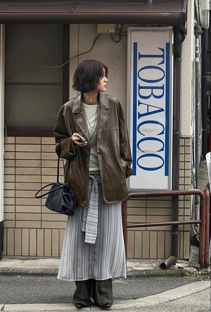 Woman with short hair wearing a leather jacket and striped skirt on a street