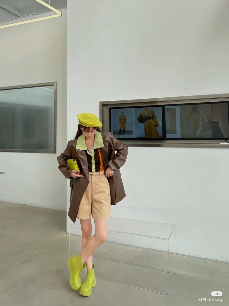 Woman in a brown blazer, khaki shorts, and lime green accessories indoors