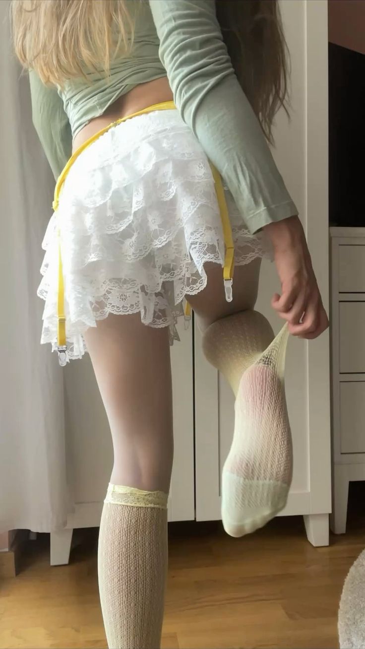 Person in a lace skirt and stockings, pulling on a sock