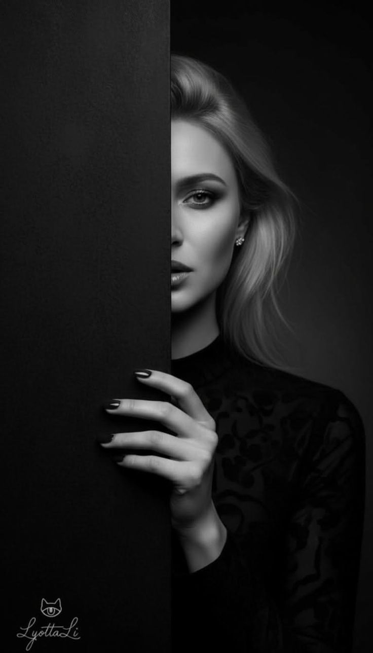 Woman with blonde hair and dark makeup peeking from behind a black panel