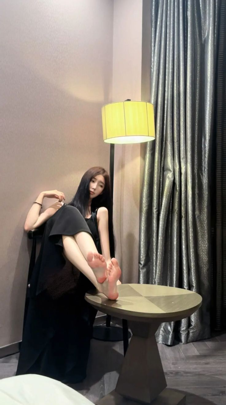 Woman in a black dress with bare feet resting on a table