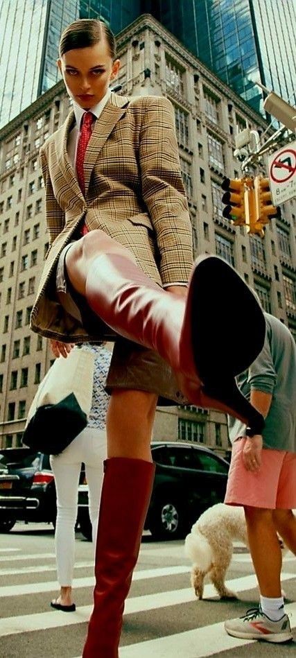 Woman in a plaid blazer and red boots on a city street from a low angle