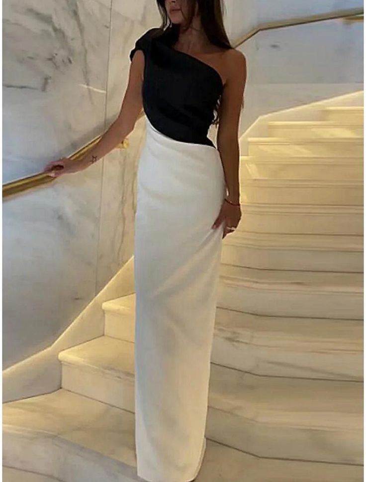 Woman in a black and white one-shoulder long dress on a marble staircase