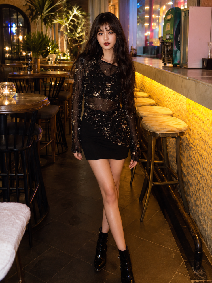 Woman in a sheer top and black dress standing in a dimly lit bar