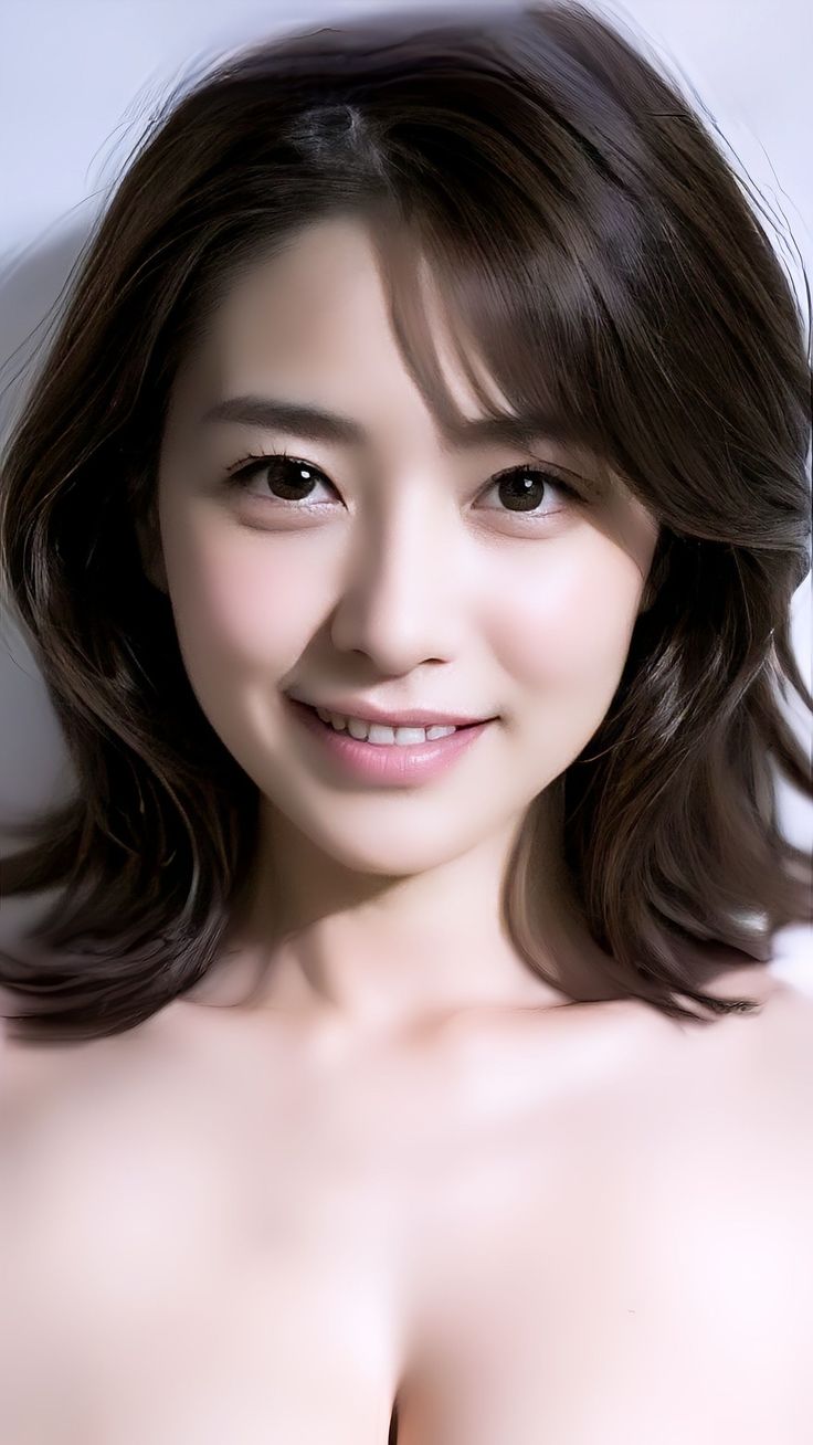 Smiling woman with dark hair and exposed shoulders, soft lighting