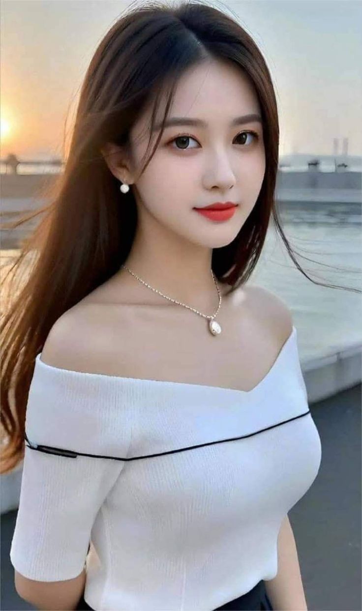 Woman with long hair wearing an off-shoulder top and jewelry at sunset
