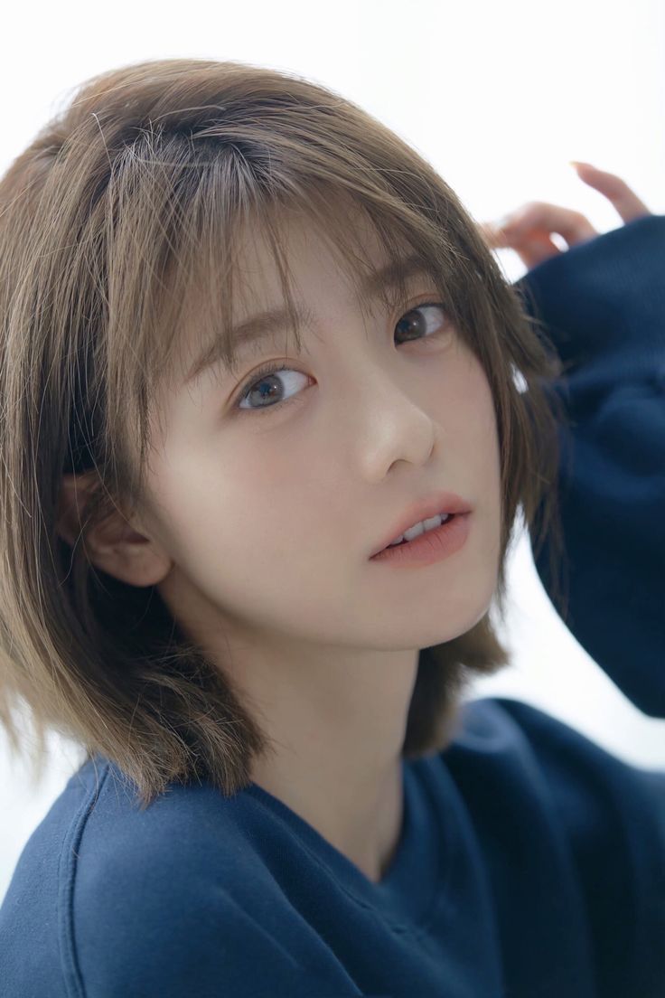 Woman with short brown hair wearing a blue shirt, looking at the camera