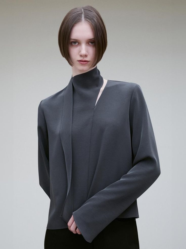 Woman with a bob cut wearing a dark grey high-collared top in a studio