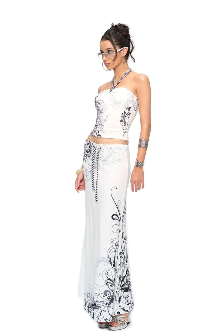 Woman in a white strapless top and maxi skirt with black scroll patterns