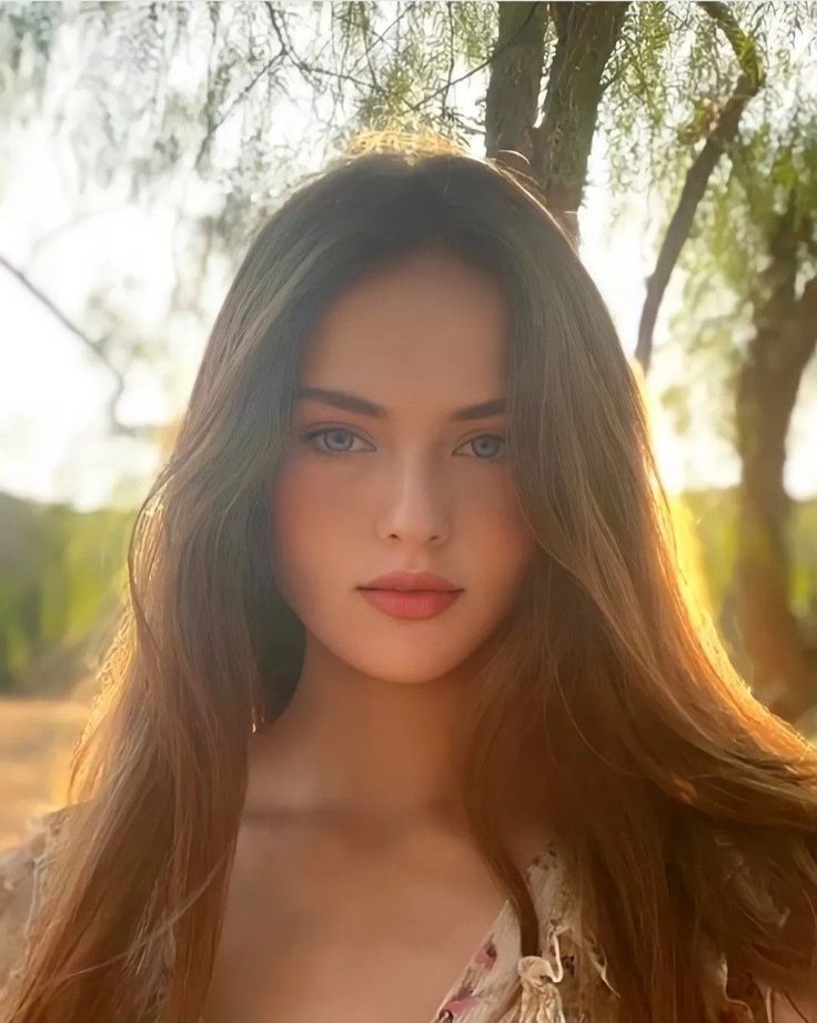 Woman with long hair and blue eyes outdoors during golden hour