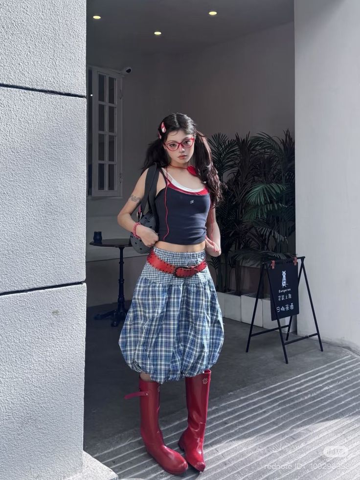 Woman in a plaid skirt, red boots, and crop top outdoors