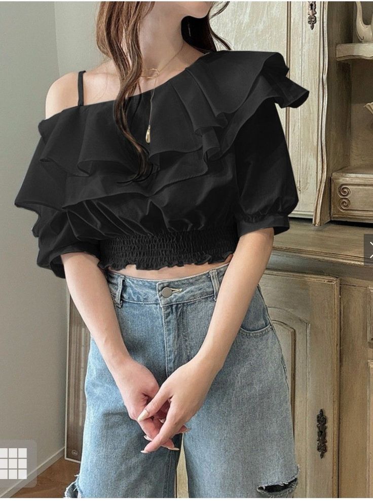 Woman in a black ruffled off-shoulder top and blue jeans indoors