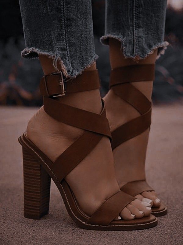 Person wearing brown strappy heels and distressed jeans outdoors