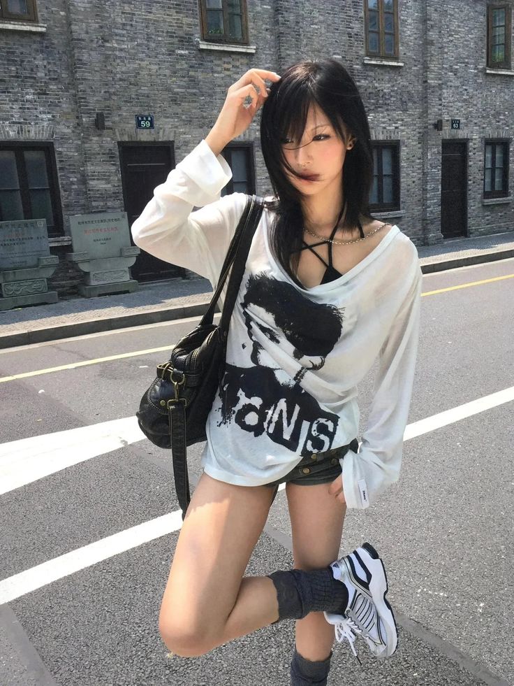 Woman with black hair wearing an oversized shirt and shorts on a street