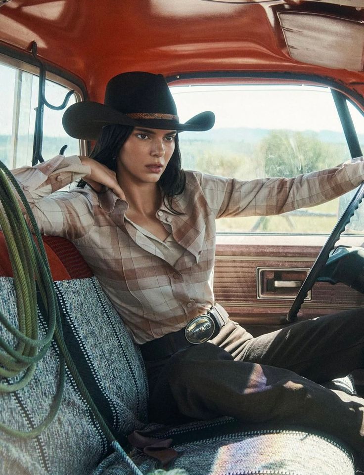 Woman in a cowboy hat and plaid shirt sitting in a truck