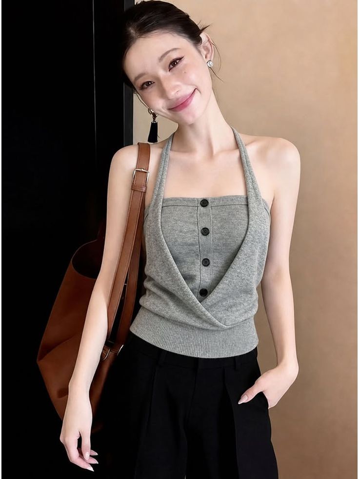 Woman in a gray halter top and black pants with a brown bag