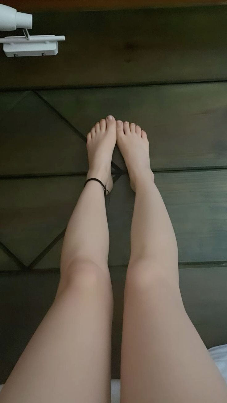 Pair of legs and feet with an anklet, viewed from above indoors