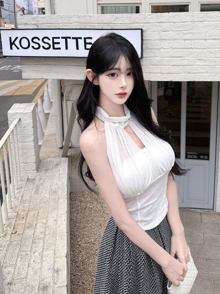 Woman with long black hair in a white halter top and pleated skirt outdoors