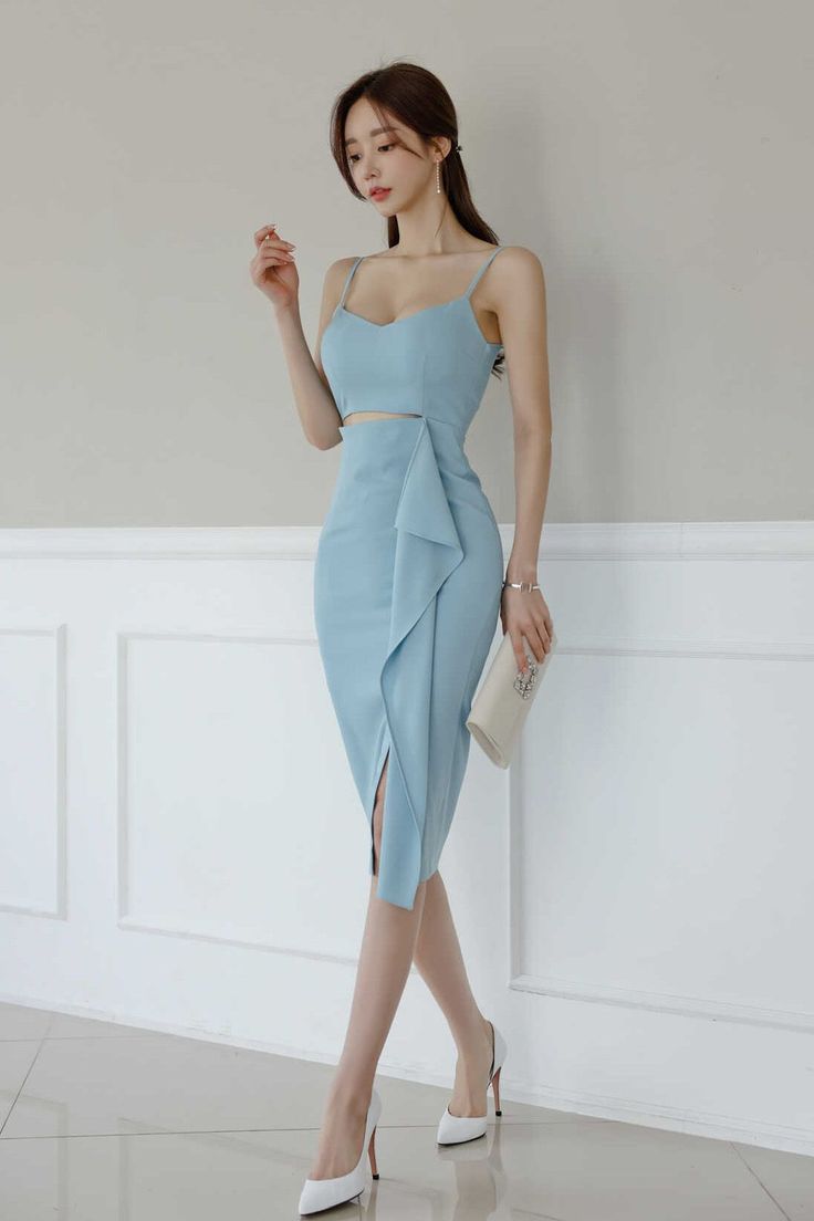 Woman in a light blue dress and white high heels holding a clutch bag