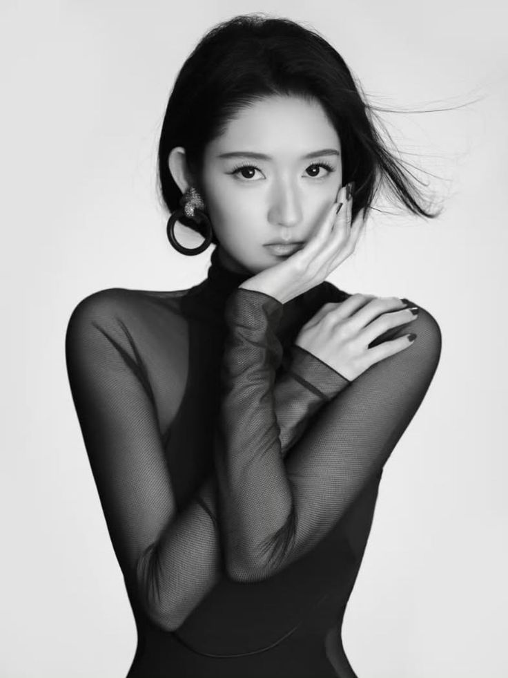 Woman in a sheer black top and large earrings posing in a studio