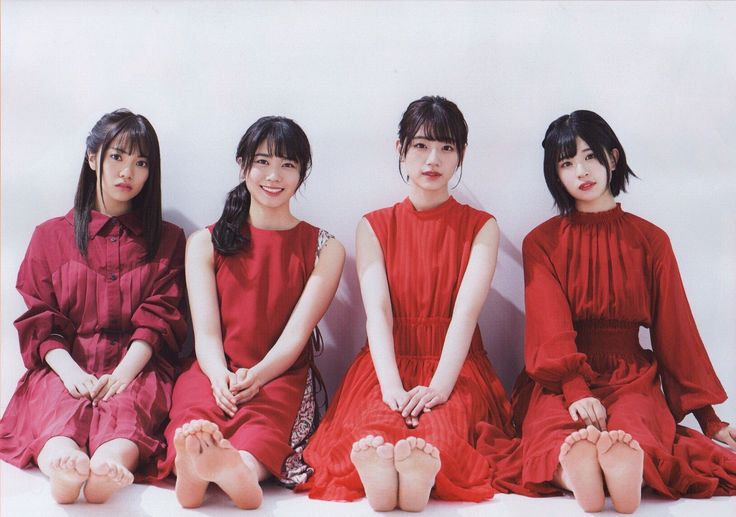 Four women in red dresses sitting on the floor with bare feet
