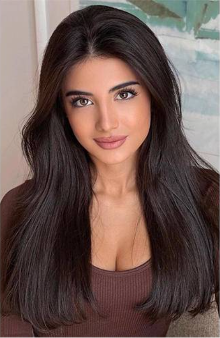 Woman with long dark hair wearing a brown top, captured in a portrait shot
