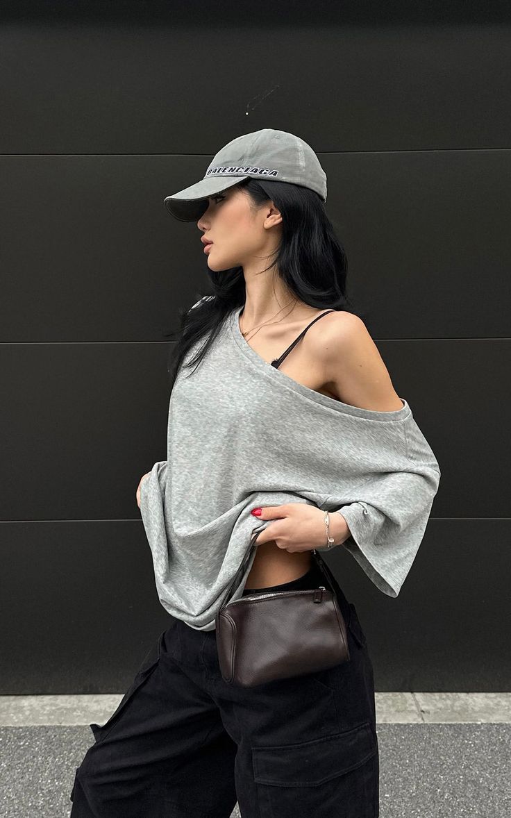 Woman in a grey t-shirt and black cargo pants with a baseball cap