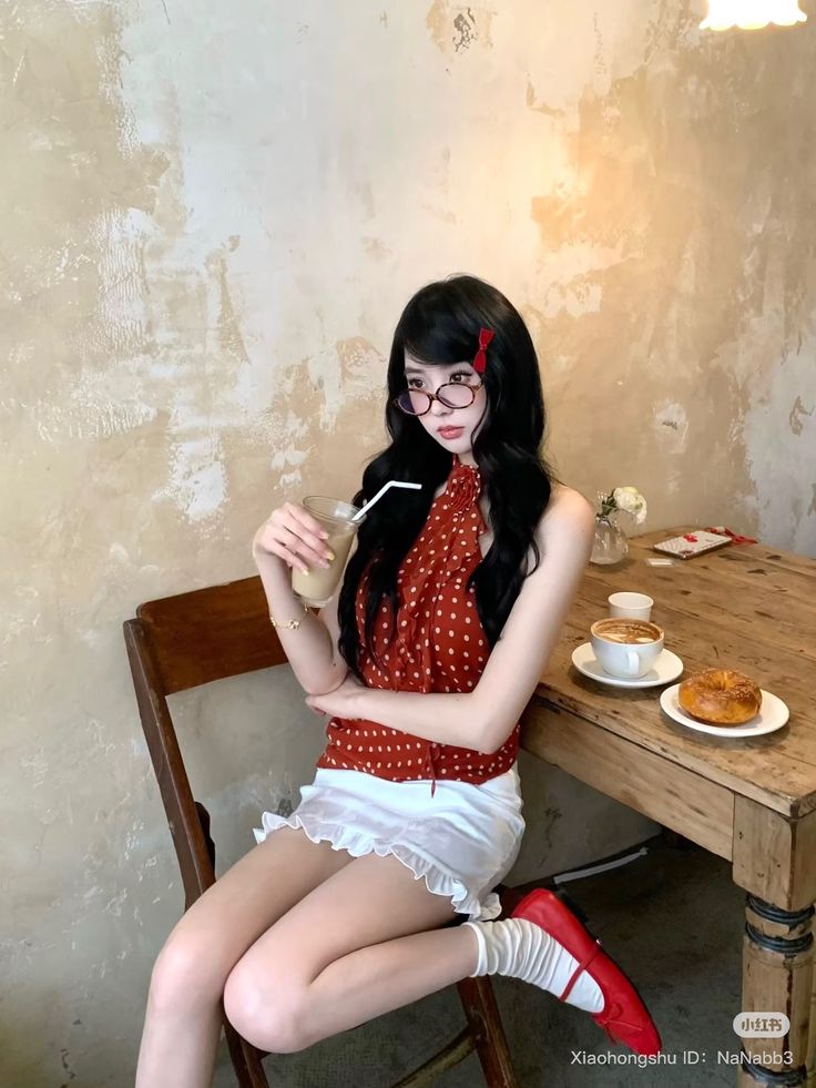 Woman with long black hair and glasses sitting at a cafe table