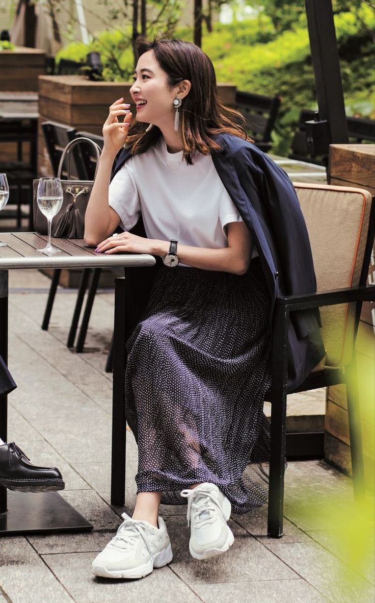 Woman in a polka dot skirt and white t-shirt sitting at an outdoor cafe