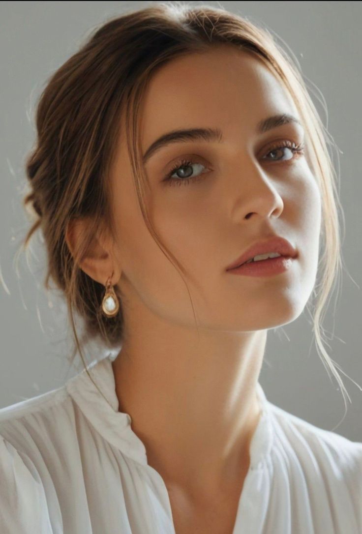 Woman with an updo hairstyle wearing a white shirt and earrings