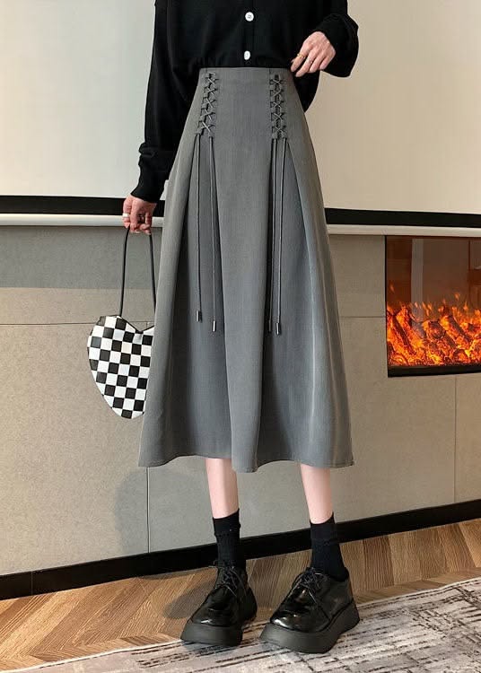 Person in a gray midi skirt and black cardigan holding a checkered heart bag