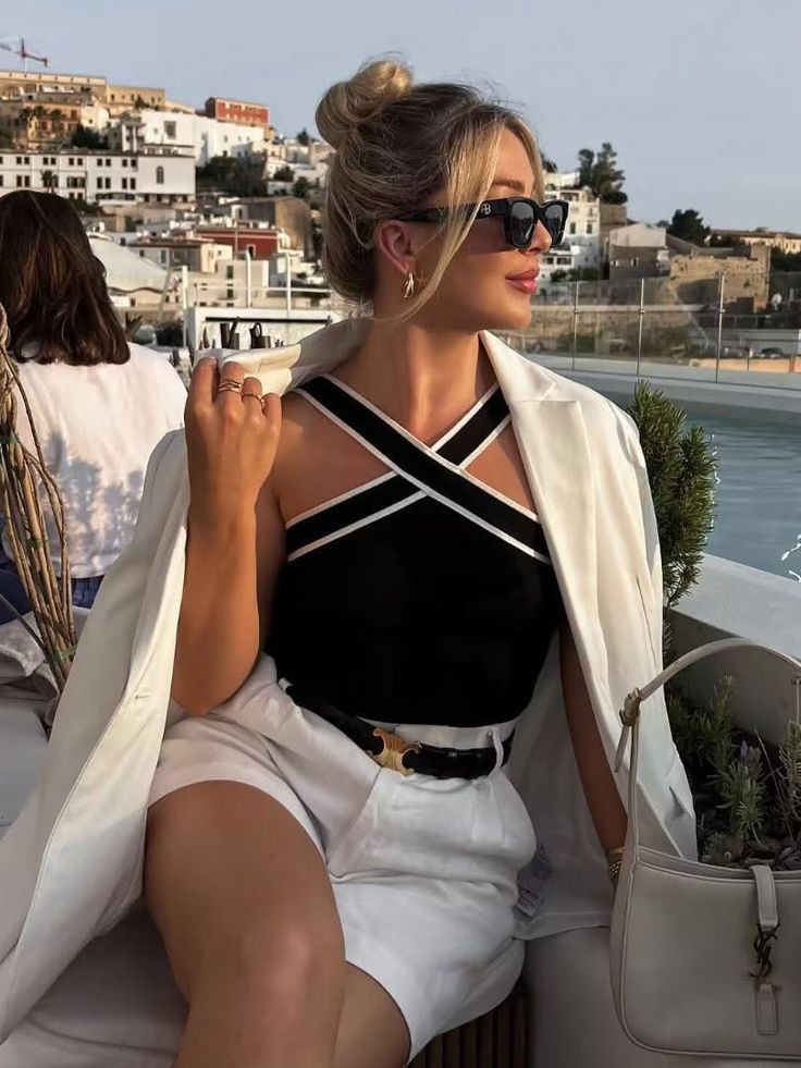 Woman in a white blazer and black top with a cityscape in the background