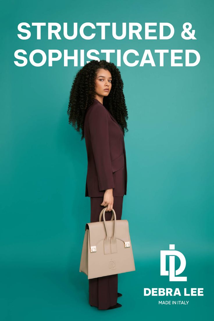 Woman in a burgundy suit holding a beige bag against a teal background