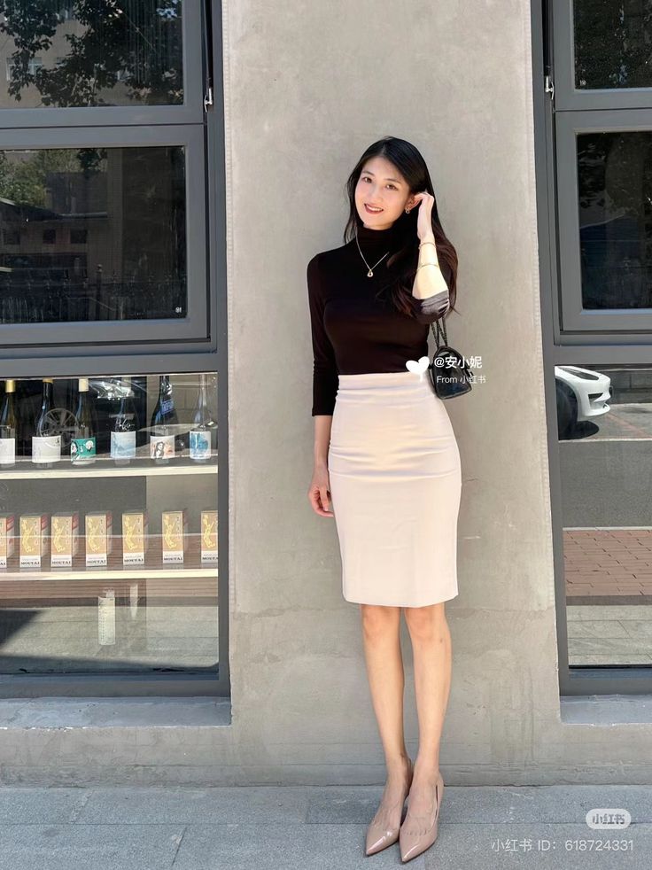 Woman in a black turtleneck and beige pencil skirt standing outdoors