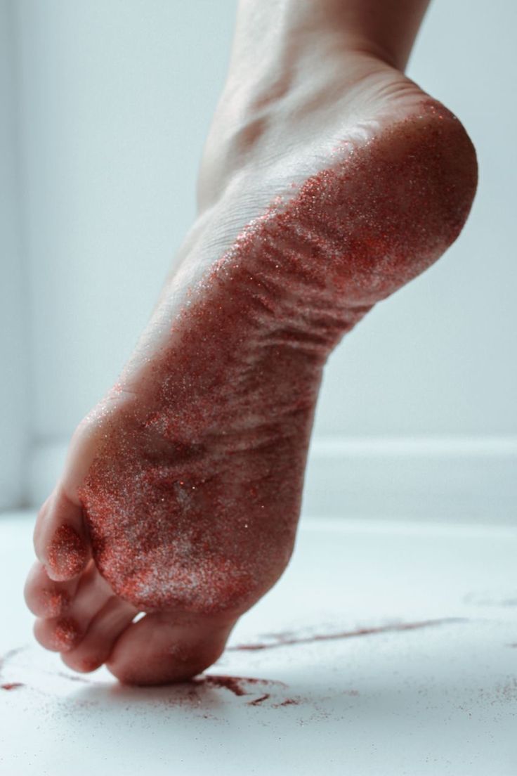 A foot covered in red glitter against a white background