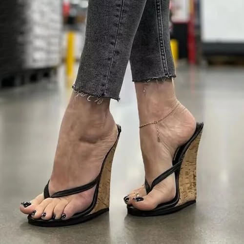 Person wearing black wedge sandals and jeans with an anklet