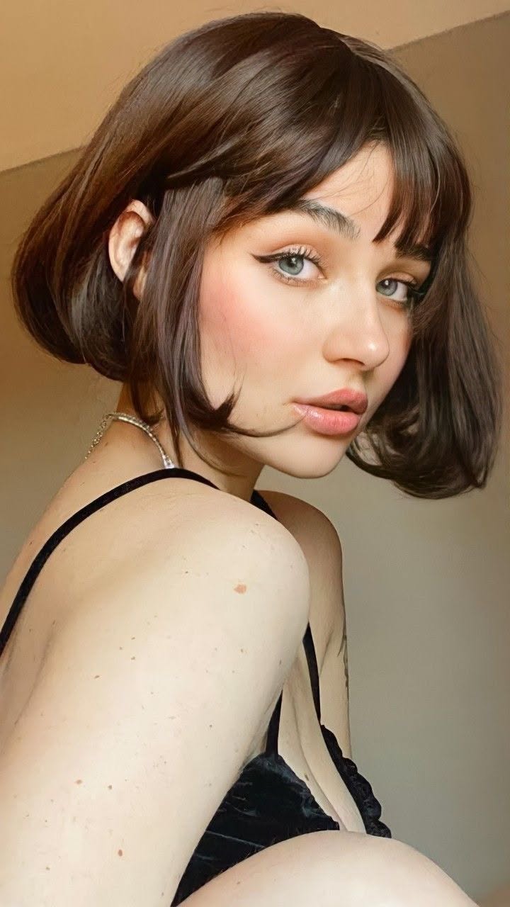 Woman with short brown hair and blue eyes wearing a black top