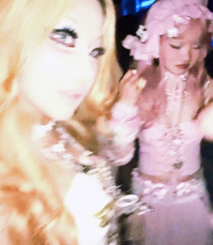 Two women with long hair, one in a pink dress, with soft lighting