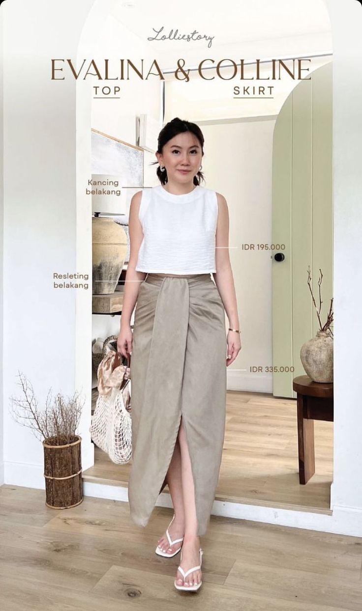 Woman in a white crop top and a draped midi skirt standing indoors
