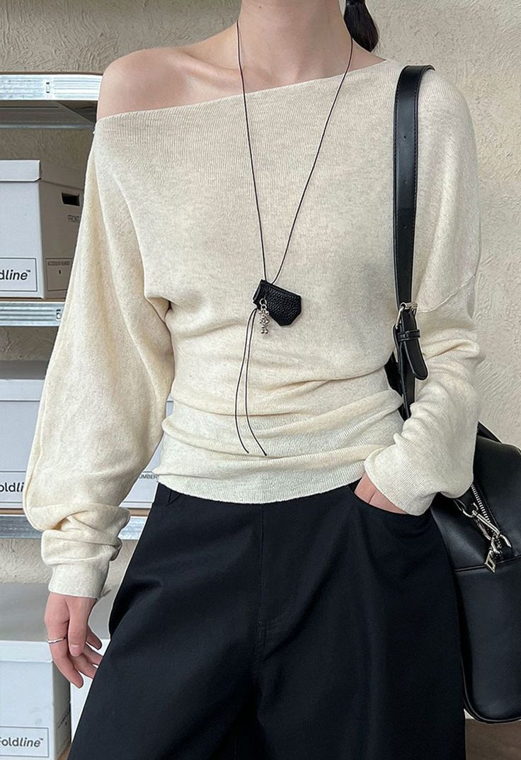 Person in an off-shoulder top and black pants with a long necklace