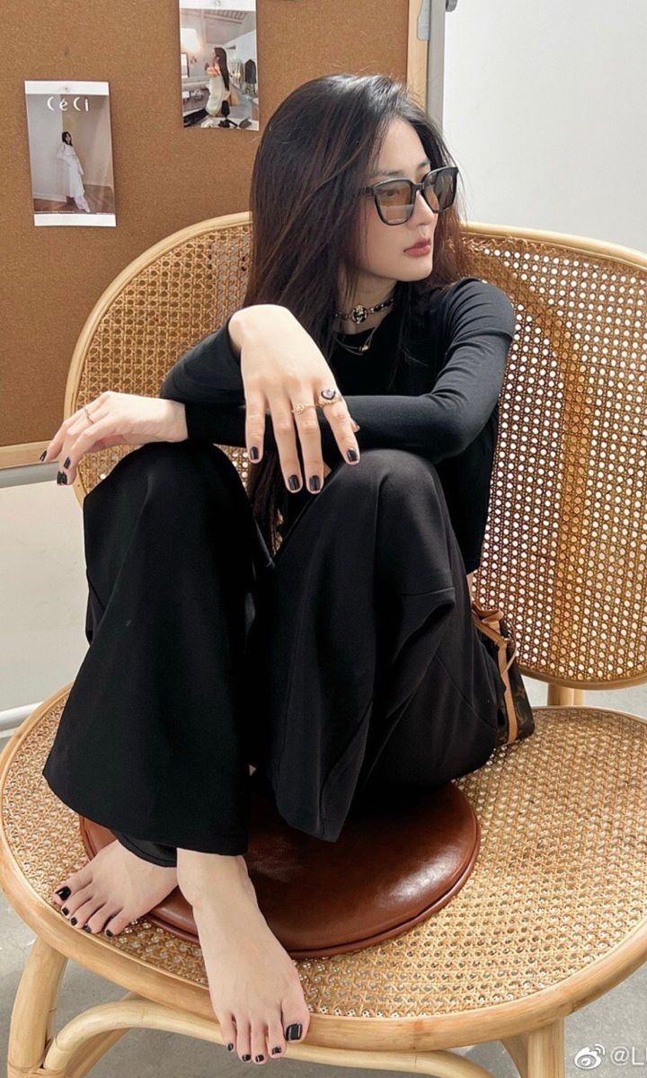 Woman with long dark hair and sunglasses sitting on a wicker chair