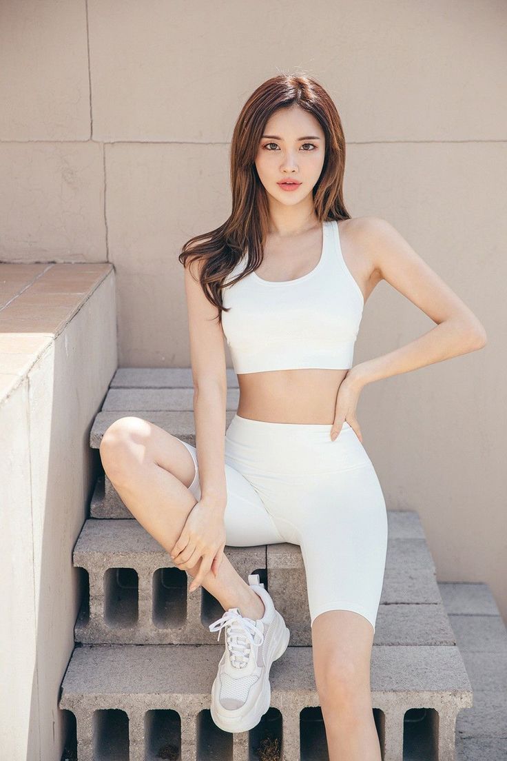 Woman in a white sports bra and biker shorts sitting on concrete steps