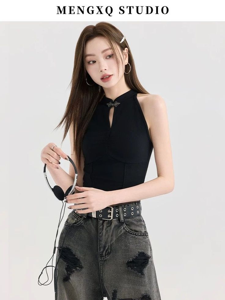 Woman with long hair wearing a black halter top and ripped jeans, holding headphones