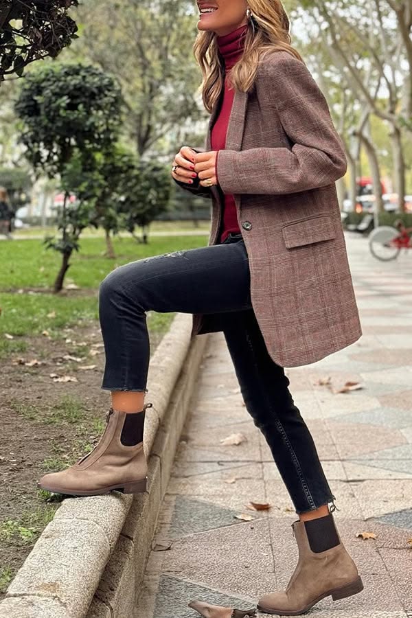 Woman in a plaid blazer and black jeans posing outdoors
